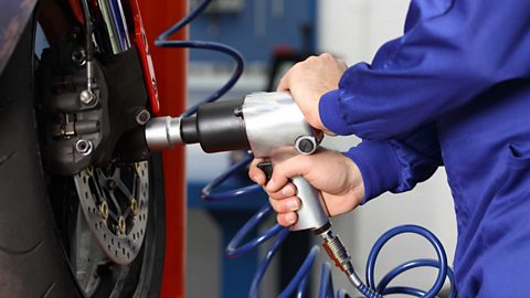 A motorcycle mechanic using an impact wrench