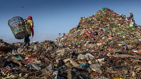 Man climbing a landfill mountain (Credit: Getty Images)
