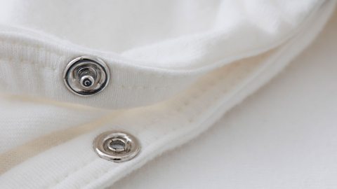 A close up of an open press stud on white fabric