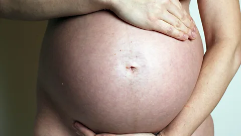 A pregnant woman holding her bare stomach (Credit: Getty Images)