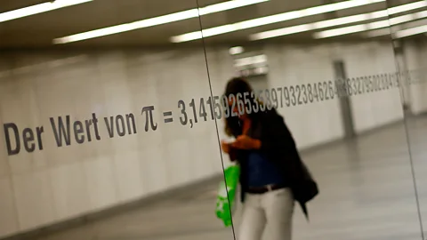Reflection of a woman walking past a mirror with the numbers of pi inscribed on it (Credit: Getty Images)