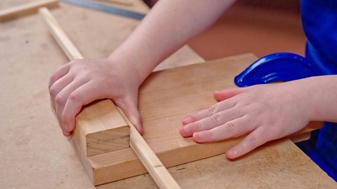 Child holding wood in bench hook