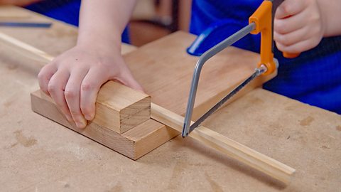 A junior hacksaw cutting wood.