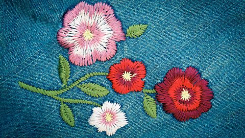 Pink and red flowers embroidered onto denim fabric