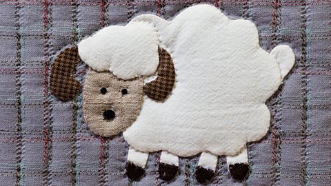 A cute sheep made from sewn patches then attached to fabric