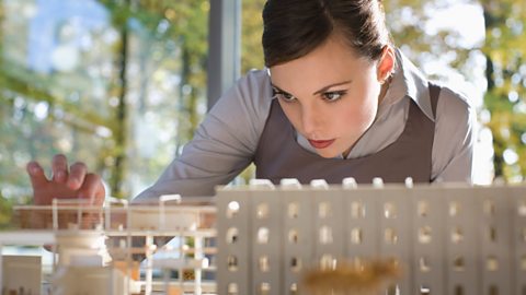 A woman making a detailed model of a building