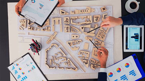 A birds eye view of a prototype of a street layout, with 3D buildings made from wood or card.