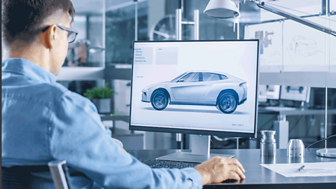 A man looking at a 3D model of a car on a computer screen.