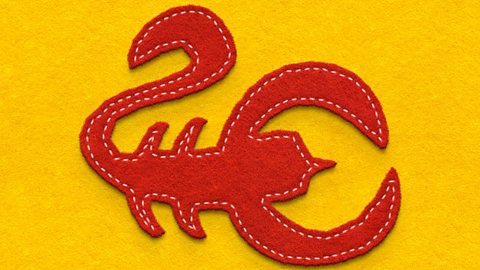 A scorpion-shaped piece of fabric sewn onto yellow fabric by a running stitch