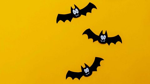 Appliqué patches shaped like bats with eyes and teeth glued onto yellow material