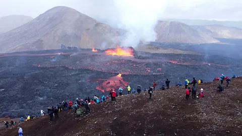 Tourists watching lava flow from rim of volcano