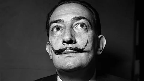 Salvador Dalí photographed face-on in black and white, showing his famous large, thin and curled moustache (Credit: Getty Images)