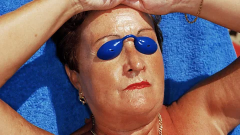 Brighty coloured photo of woman sunbathing wearing goggles (Credit: Martin Parr)