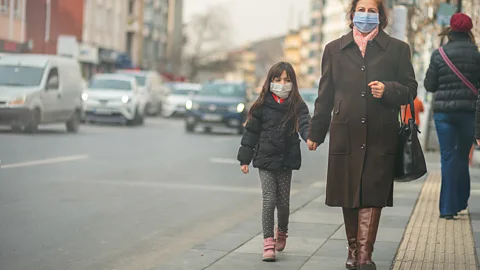 A mother and daughter both wear face masks to protect themselves from air pollution