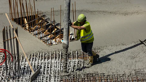 A construction worker pouring concrete foundations (Credit: Getty Images)
