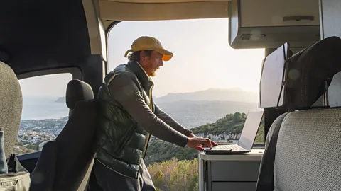 A remote worker using his laptop in the back of a camper van (Credit: Getty Images)