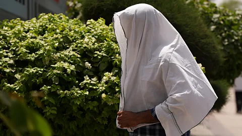 A pedestrian covers their head with a sheet to protect themselves from the Sun (Credit: Getty Images)