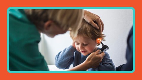 Female doctor examining a boy's ear with an otoscope in hospital.