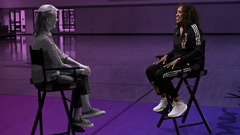 Katty Kay and Jackie Joyner-Kersee facing each other on chairs. The image is stylised with a purple wash over it, apart from Joyner-Kersee who is in full colour (Credit: BBC/ Scott Rovak)