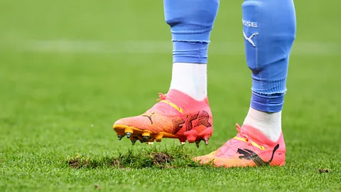 A footballer's boot treading on a rut in the turf (Credit: Getty Images)