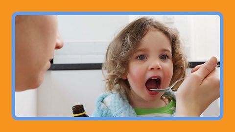 A child receiving medicine from a bottle.