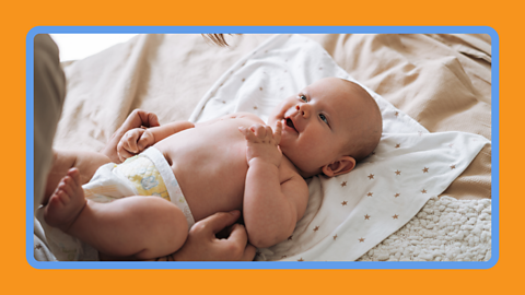 A baby laughing laying on their back.