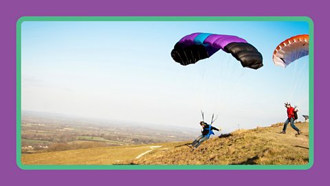 Two parasailors jumping from a moor in the UK to begin flying.