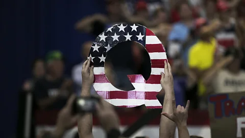 Hands hold up a letter Q painted with the US flag (Credit: Getty Images)