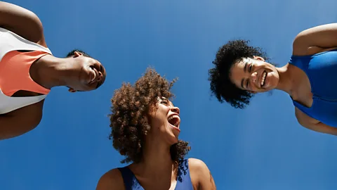 Three women looking down and smiling (Credit: Getty Images)