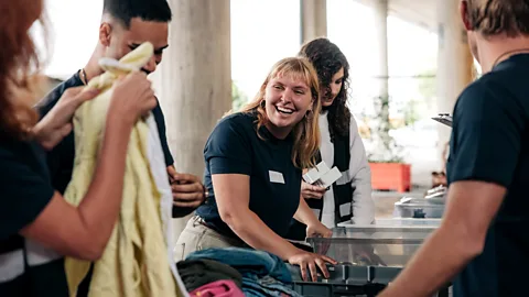 A female volunteer helps to sort clothes with group of people (Credit: Getty)