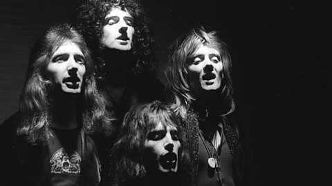 A black and white photo of the faces of four male singers posed in a diamond shape.  Their faces are lit with strong lights from above.