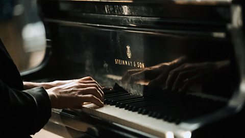 A pianist sat at a Steinway and Son piano playing with both hands.