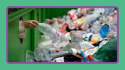 A woman depositing a bottle in a recycling bank.