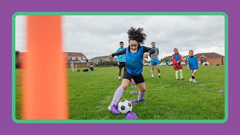 A girl playing football in a field in the UK.