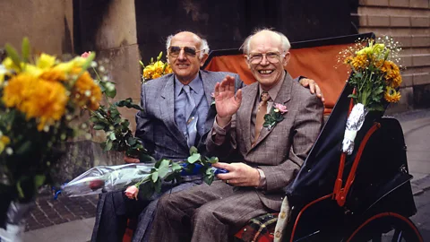 Two men sitting on a cart surrounded by flowers (Credit: Getty Images)