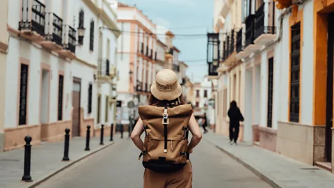 Woman standing with backpack in the middle of a street (Credit: Getty Images)