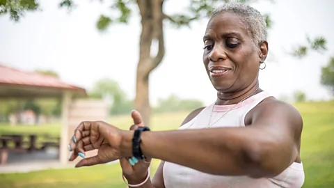 A woman checks her smartwatch outdoors on a walk (Credit: Getty Images)