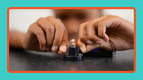 A bulb lit up in a science experiment held by a child.