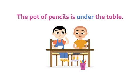 two boys sat at a table with a pot of pencils underneath them, above them it says the pot of pencils is under the table