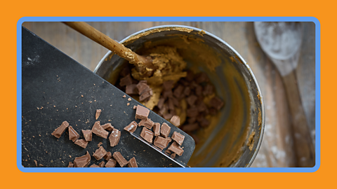 Chocolate being emptied into a mixing bowl with cake mix.