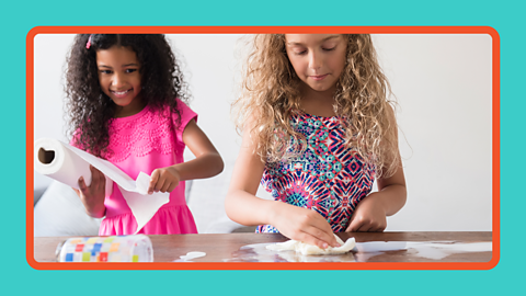 Two girls mopping up a spill with paper towels.