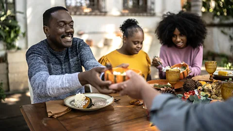 People at table grabbing slices of pizza (Credit: Getty Images)