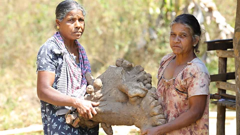 Two women from the Vetta Kuruman tribe stand next to one of the giant tubers (Credit: Sai Krishan, Thirunelly Tribal Special Intervention Programme)