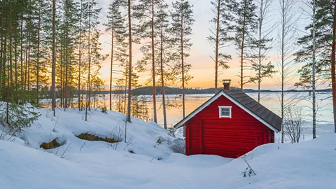 Wooden red cabin in Sweden and snow at sunset (Credit: Getty Images)