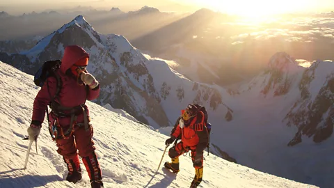 Two climbers on the side of a snowy mountain with peaks behind them (Credit: Lars Nessa)