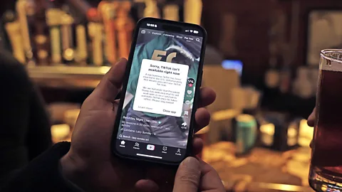 A person holding a phone with the TikTok app open, which shows the notice saying 'Sorry, TikTok isn't available right now' (Credit: Getty Images)