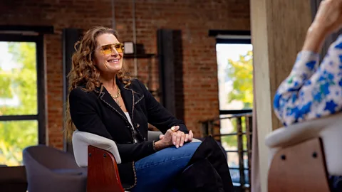 Actress and model Brooke Shields chats with BBC's Katty Kay while wearing sunglasses and a tailored black jacket (Credit: Natassja Ebert)