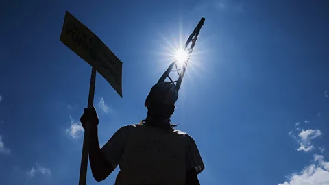 A silhouette of an anti-fracking protester against a blue sky (Credit: Getty Images)