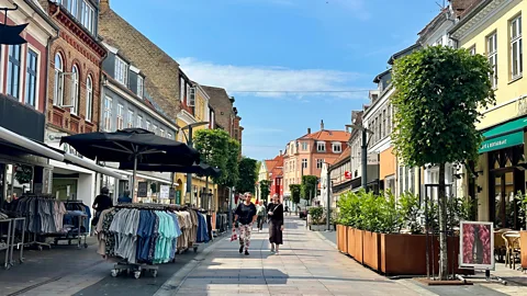 Pedestrians walk down a paved street lined with shops and restaurants in Kalundborg, Denmark (Credit: Adrienne Murray)