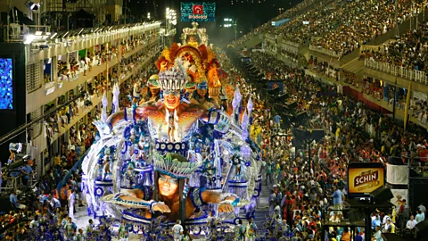 A Carnival parade surrounded by crowds on a street in Rio de Janeiro (Credit: Alamy)